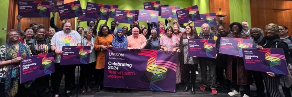 Regional Council AGM delegates holding placards and a banner to celebrate 2024: Year of LGBT+ Workers.